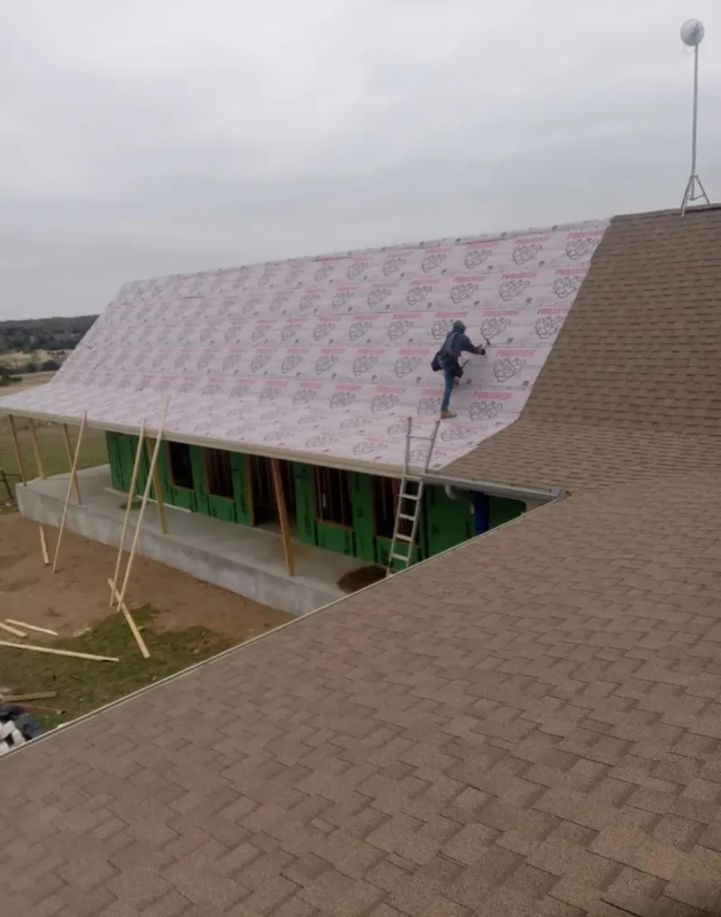 Worker preparing underlayment for a metal roof installation in Highlands
